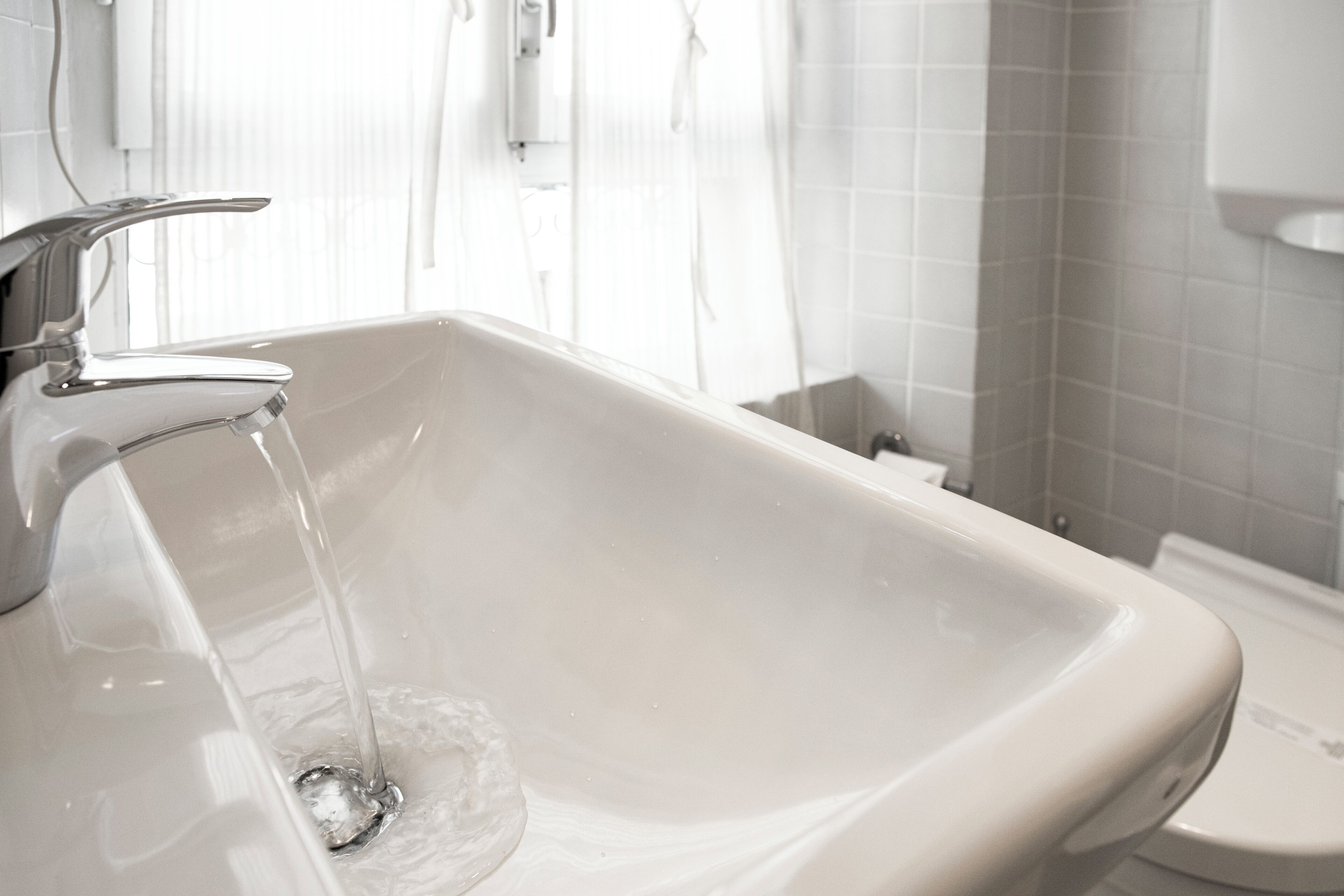 Un baño con lavamanos blanco, grifo e inodoro.