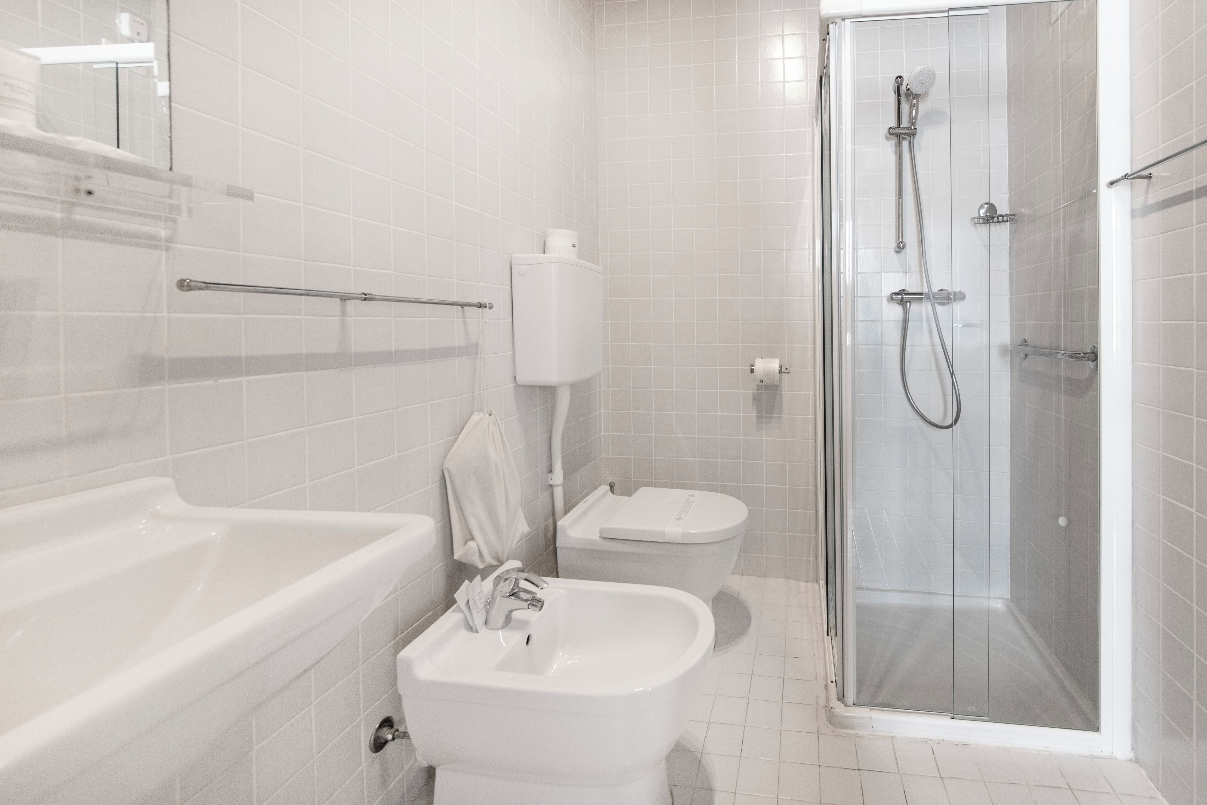 A modern bathroom with a bathtub, sink, toilet, and glass-enclosed shower.