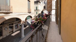 A narrow street with buildings on either side, a balcony with flowers, and a pharmacy. - Hotel Broletto Mantova - centro storico (Mantua)