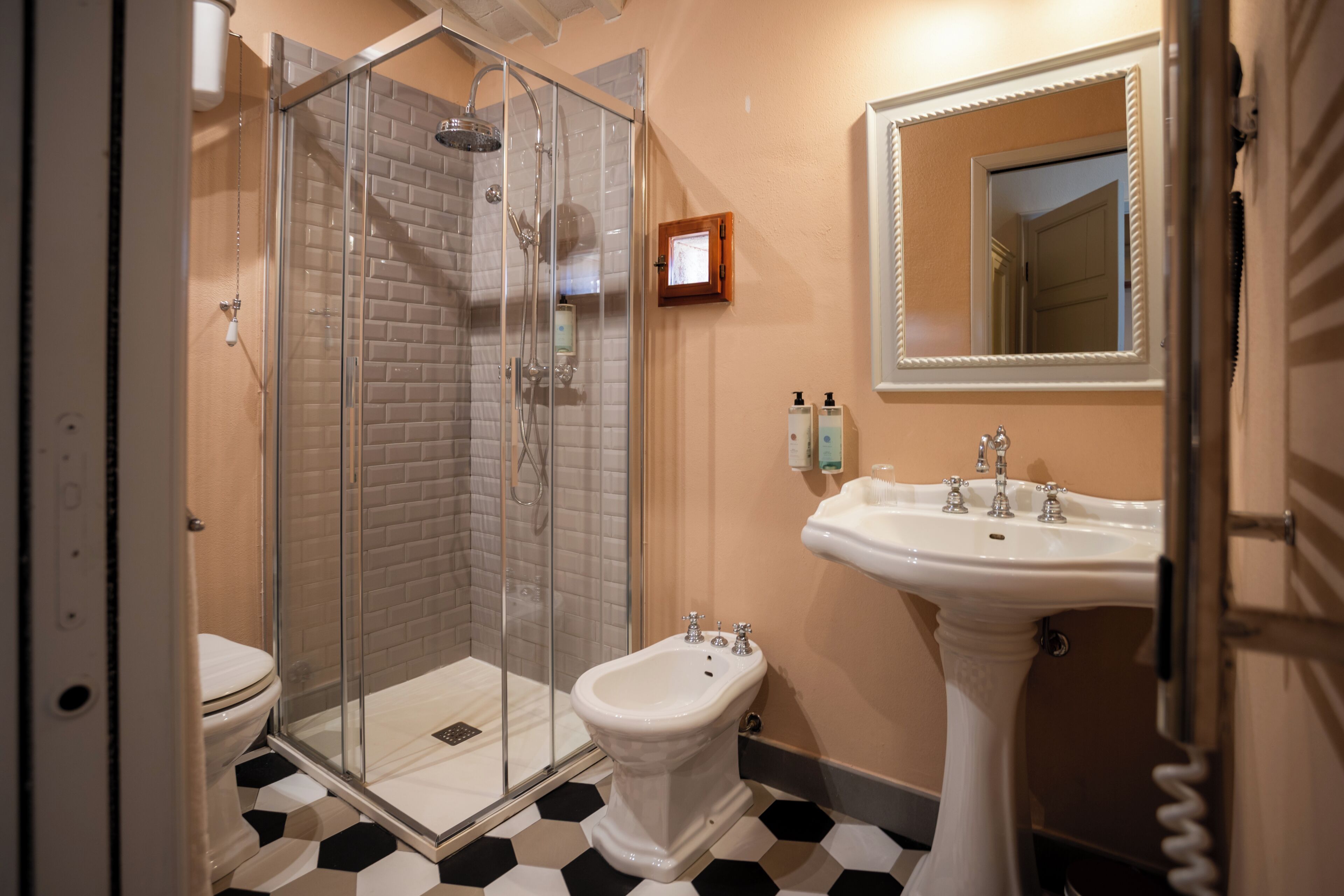 A bathroom with a glass-enclosed shower, a pedestal sink, and a toilet.