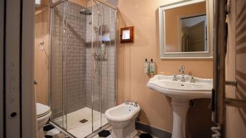 A bathroom with a glass-enclosed shower, a pedestal sink, and a toilet.