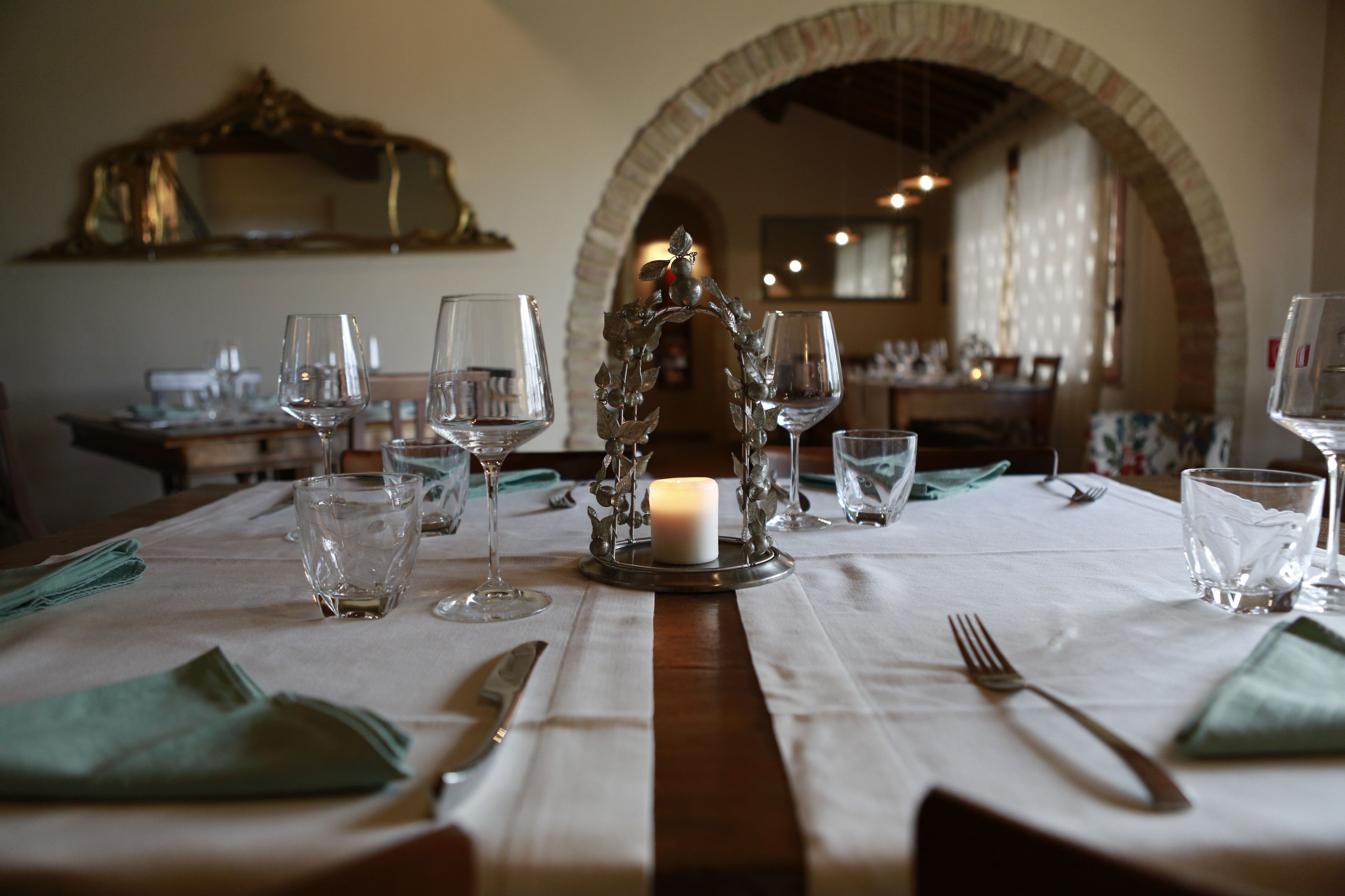 Una mesa de comedor con copas de vino, un candelabro y un espejo en la parte superior.