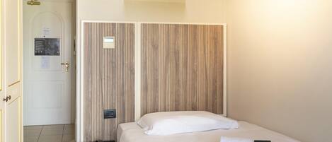 Habitación de hotel con cama, teléfono en la mesita de noche y toalla con el letrero 'No molestar'.