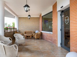 Un'area relax esterna coperta con sedie in vimini, un lampione sospeso e un muro in mattoni.