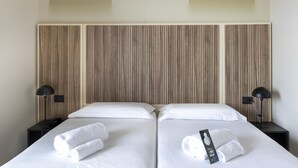 A double bed with white linens, two bedside tables with lamps, and a wooden headboard. - B&B Hotel Pomezia Cortese (Pomezia)