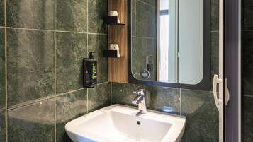 Un bagno moderno con un lavandino bianco, uno specchio e un erogatore di sapone a parete.