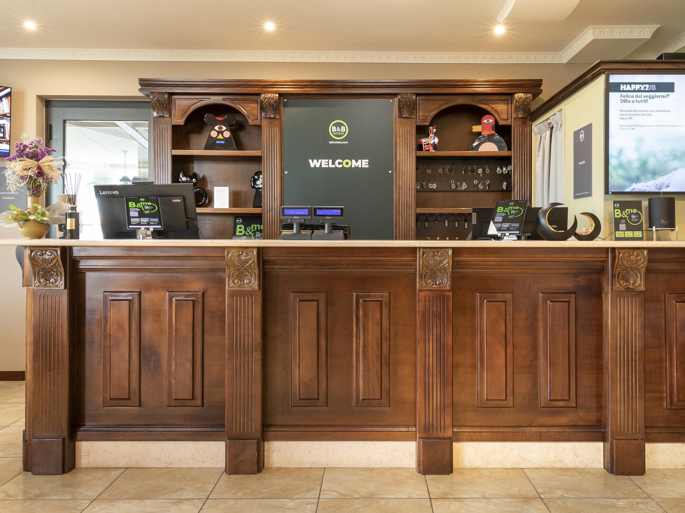 A reception desk with a 'WELCOME' sign, a digital display, and a key rack.