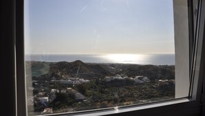 A coastal view from a window, including a hillside with buildings and a clear sky. - Hotel Mamabels (Mojacar)