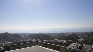 A coastal town with buildings on hills, a clear sky, and the ocean in the distance. - Hotel Mamabels (Mojacar)