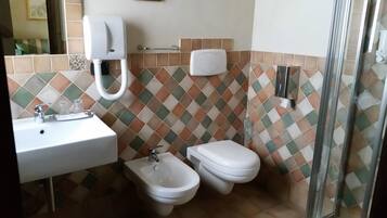 A bathroom with a sink, bidet, toilet, and a hand dryer.