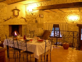 Un comedor con paredes de piedra, chimenea y una mesa lista para dos personas.