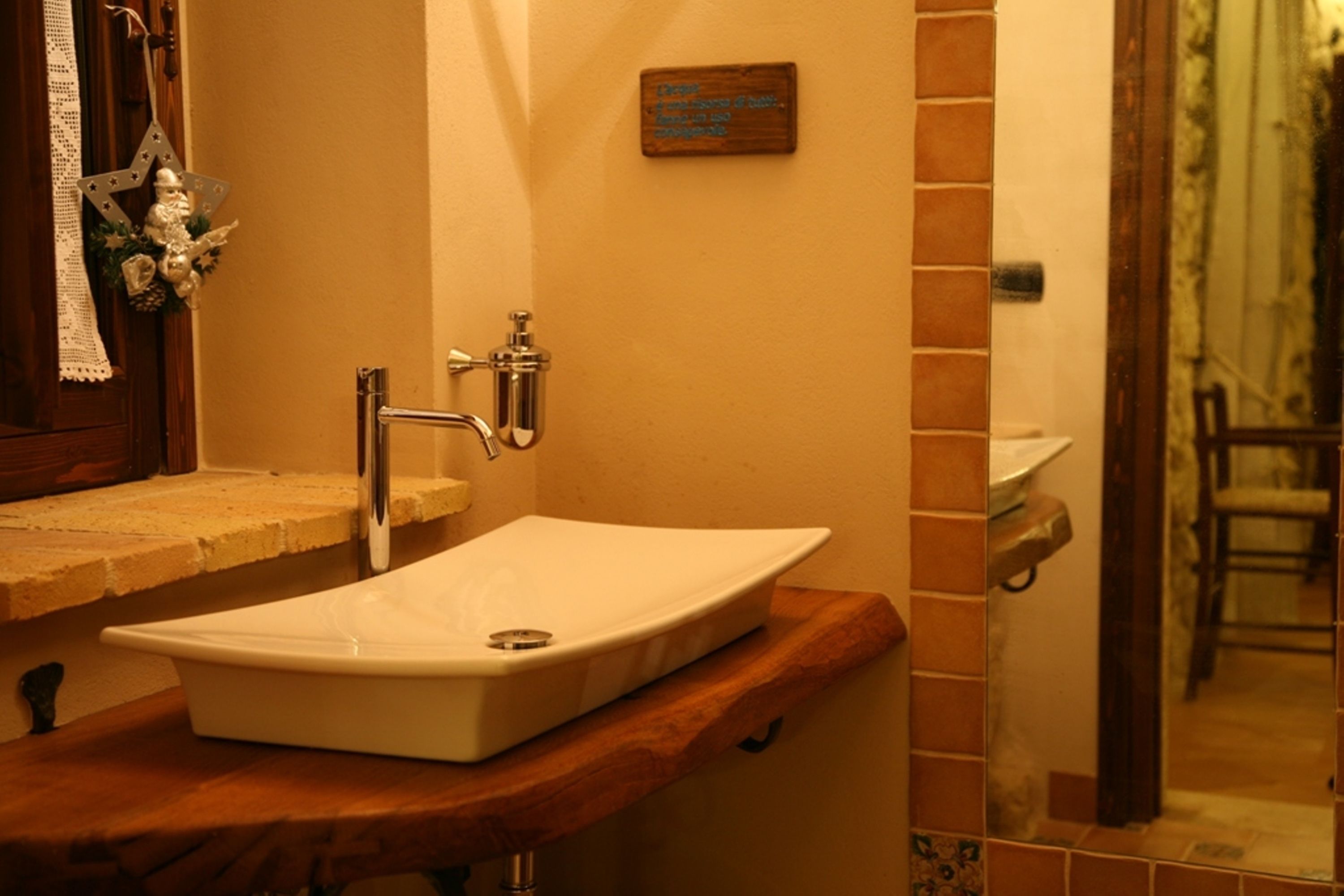 Une salle de bain avec un lavabo blanc, un plan de toilette en bois et un miroir.