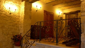 A stone staircase with wrought iron railings and wall-mounted lighting.