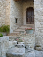 Un edificio de piedra con puerta de madera y escalones que suben hasta una ventana.