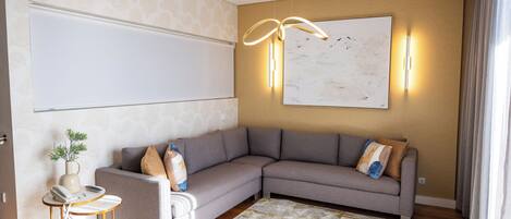 Una sala moderna con un sofá modular, una mesita auxiliar, un jarrón decorativo y un cuadro abstracto de gran tamaño en la pared.