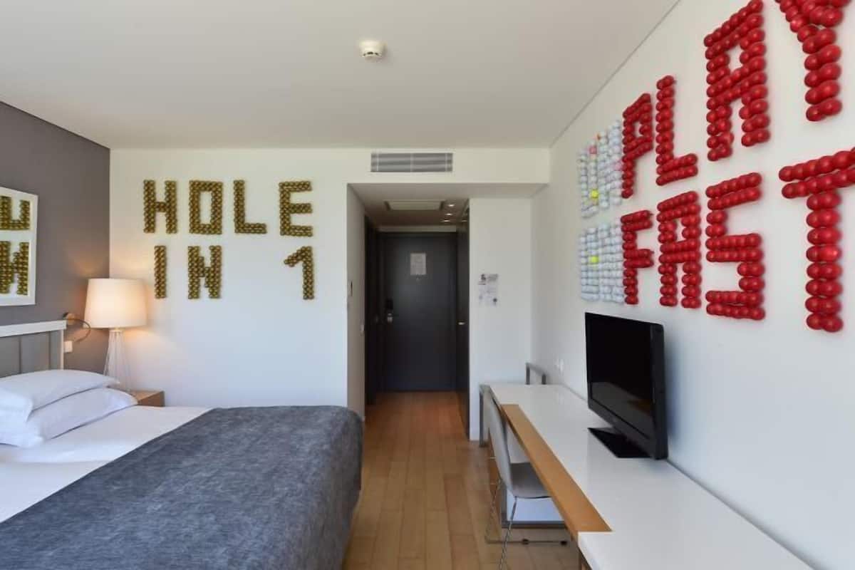 Ett modernt hotellrum med en säng, ett skrivbord och en TV.