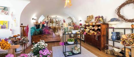 A floral shop with shelves of flowers, a wooden bench, and a rustic ceiling.
