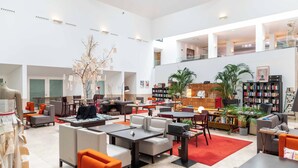 A spacious lobby with multiple seating areas, a central decorative tree, and a large bookshelf.