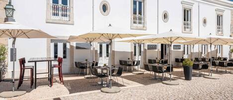 A white building with outdoor seating and umbrellas.