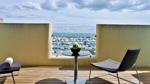 A balcony with a table and two chairs, overlooking a marina with boats.