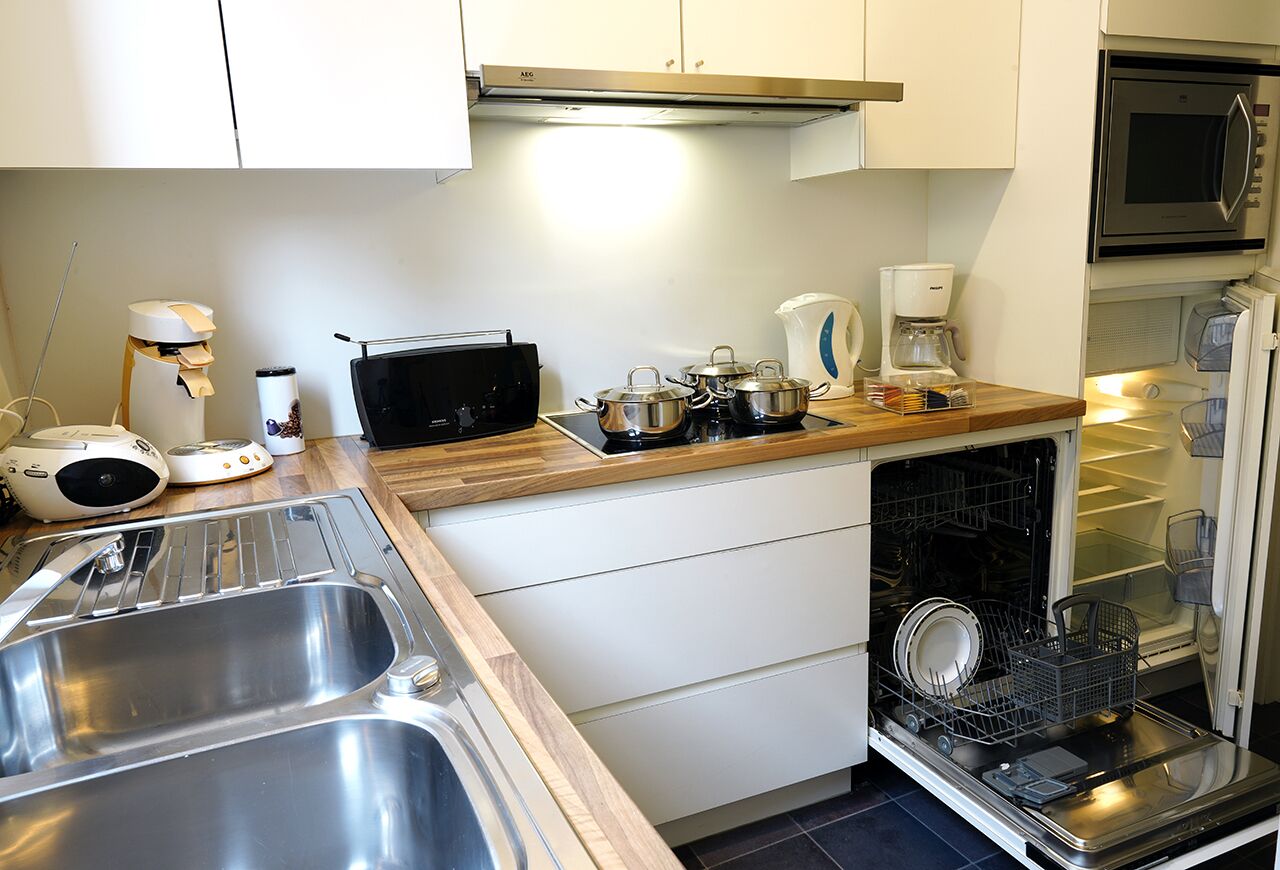 Una cocina moderna con electrodomésticos de acero inoxidable, lavavajillas integrado y cafetera.
