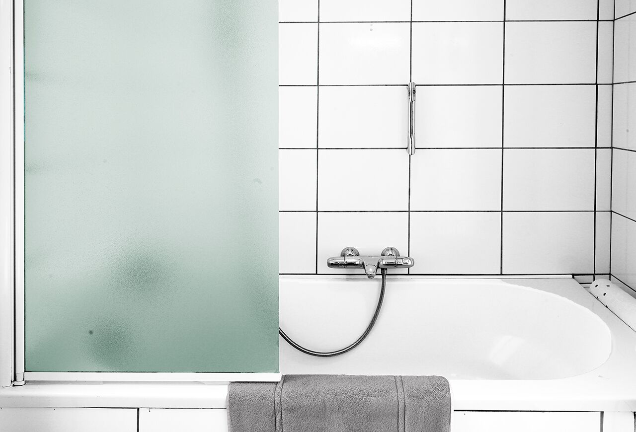 A bathroom with a white bathtub, a glass shower enclosure, and a towel rack.