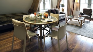 A cozy dining area with a round table, four chairs, and a coffee table. - Apartments Ypres (Ypres)
