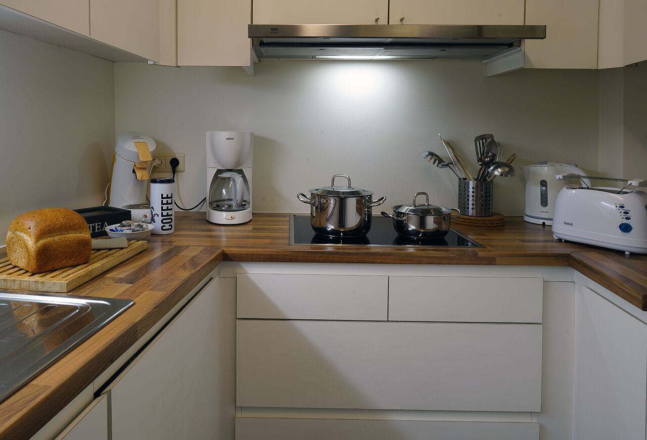 Una cocina moderna con encimera de madera, una cafetera, un tostador y un pan.