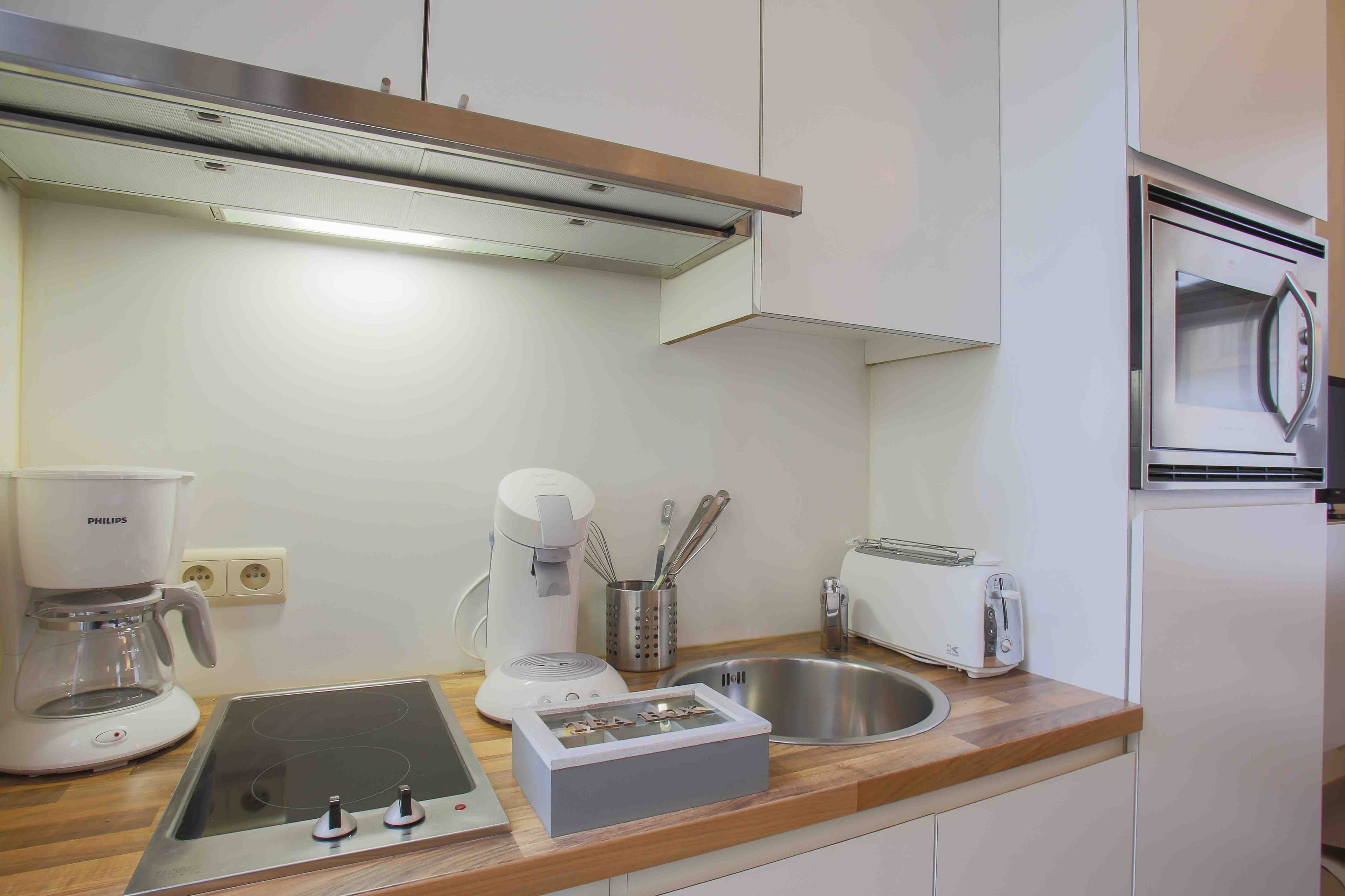 A modern kitchen with a built-in oven, a coffee maker, a toaster, and a sink.