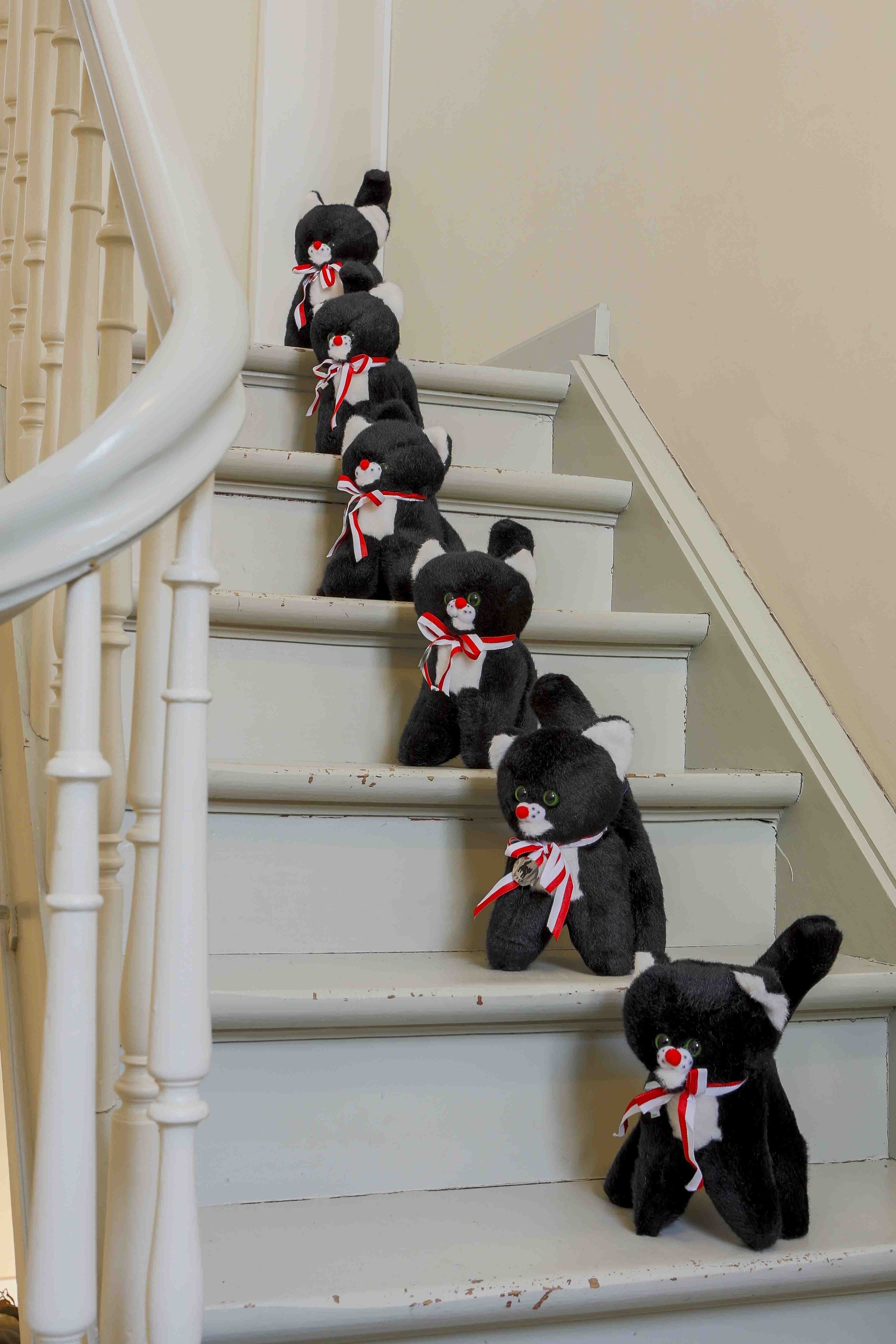 Una escalera con varios osos de peluche blancos y negros y cintas rojas.
