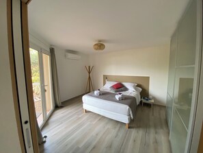 Un dormitorio moderno con una cama grande, una mesita de noche y vistas a través de un ventanal.