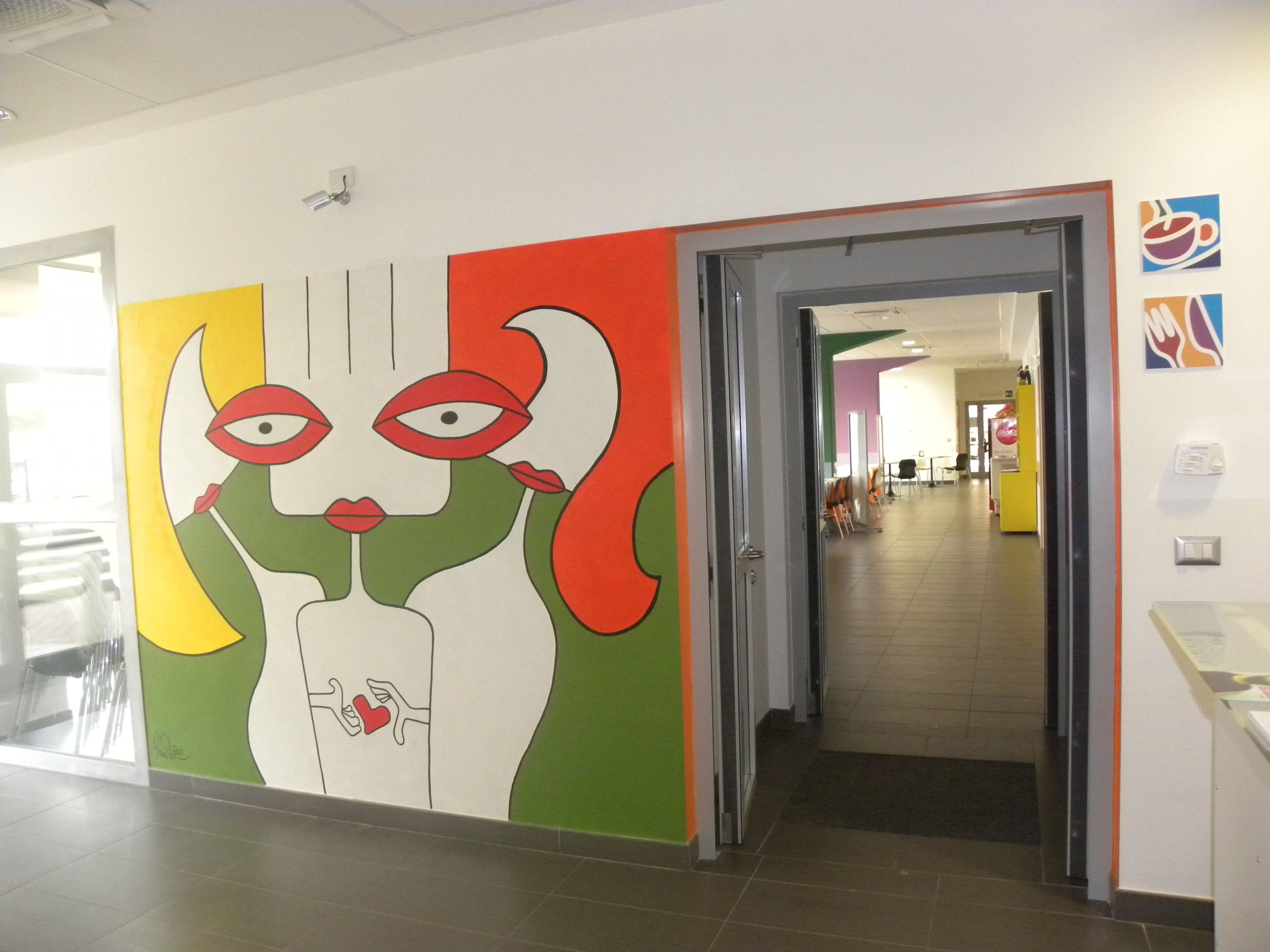 A hallway with a colorful mural, a glass door, and a tiled floor.