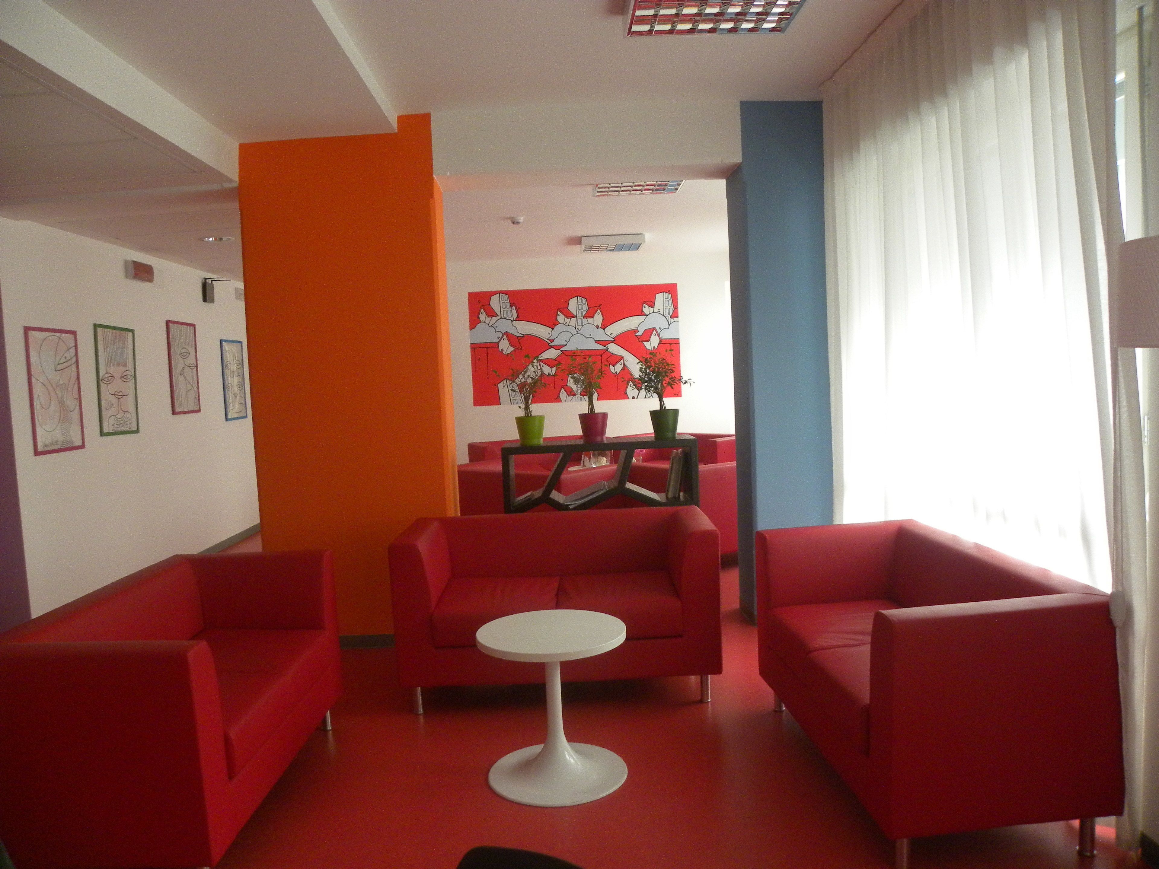 A modern room with red sofas, a white table, and artwork on the walls.