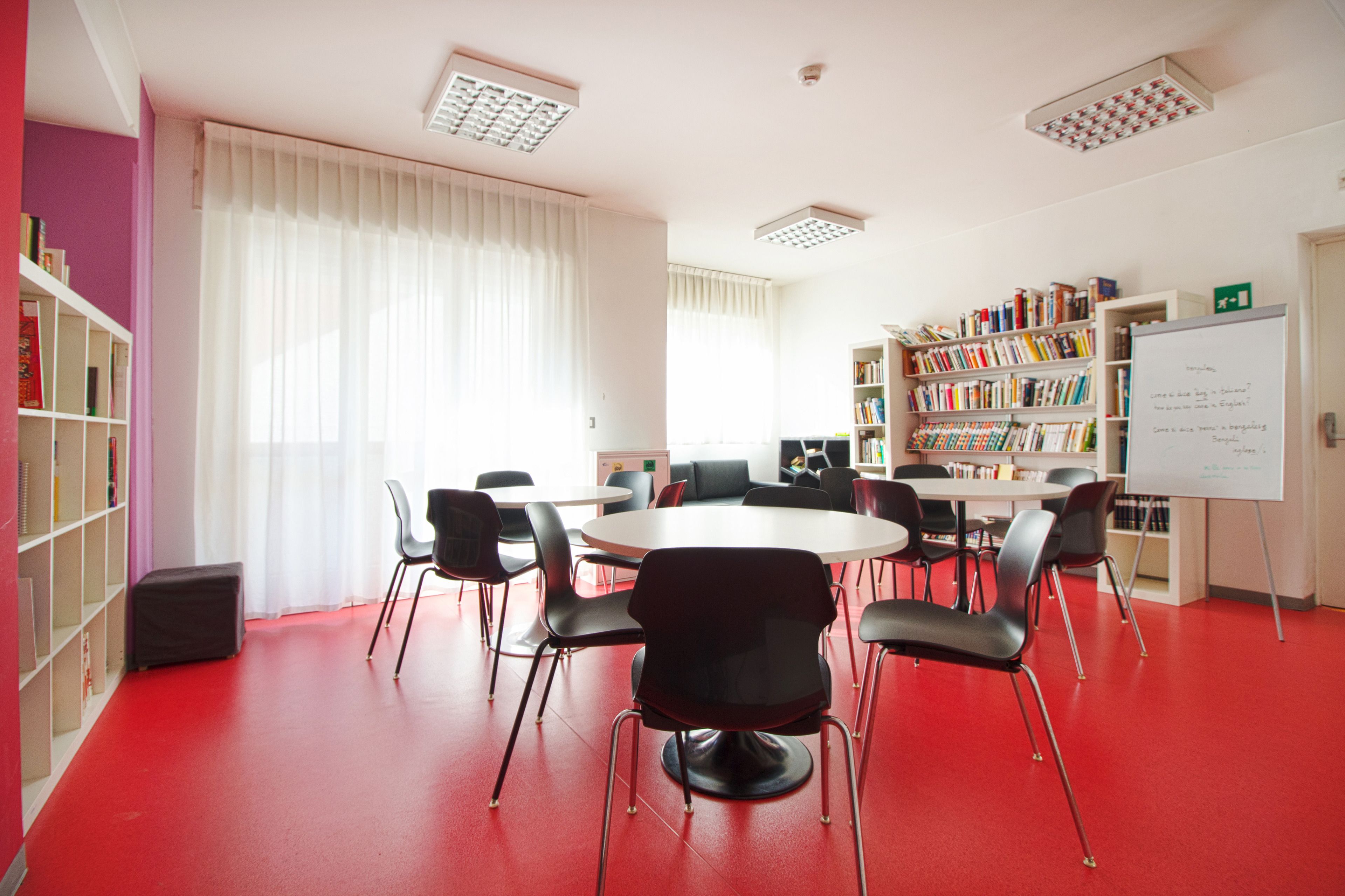 Un salón de conferencias con una mesa blanca, sillas negras, una pizarra y estanterías.