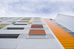 Ein modernes Gebäude mit vielen Fenstern und einer auffälligen, orange-weißen Fassade.