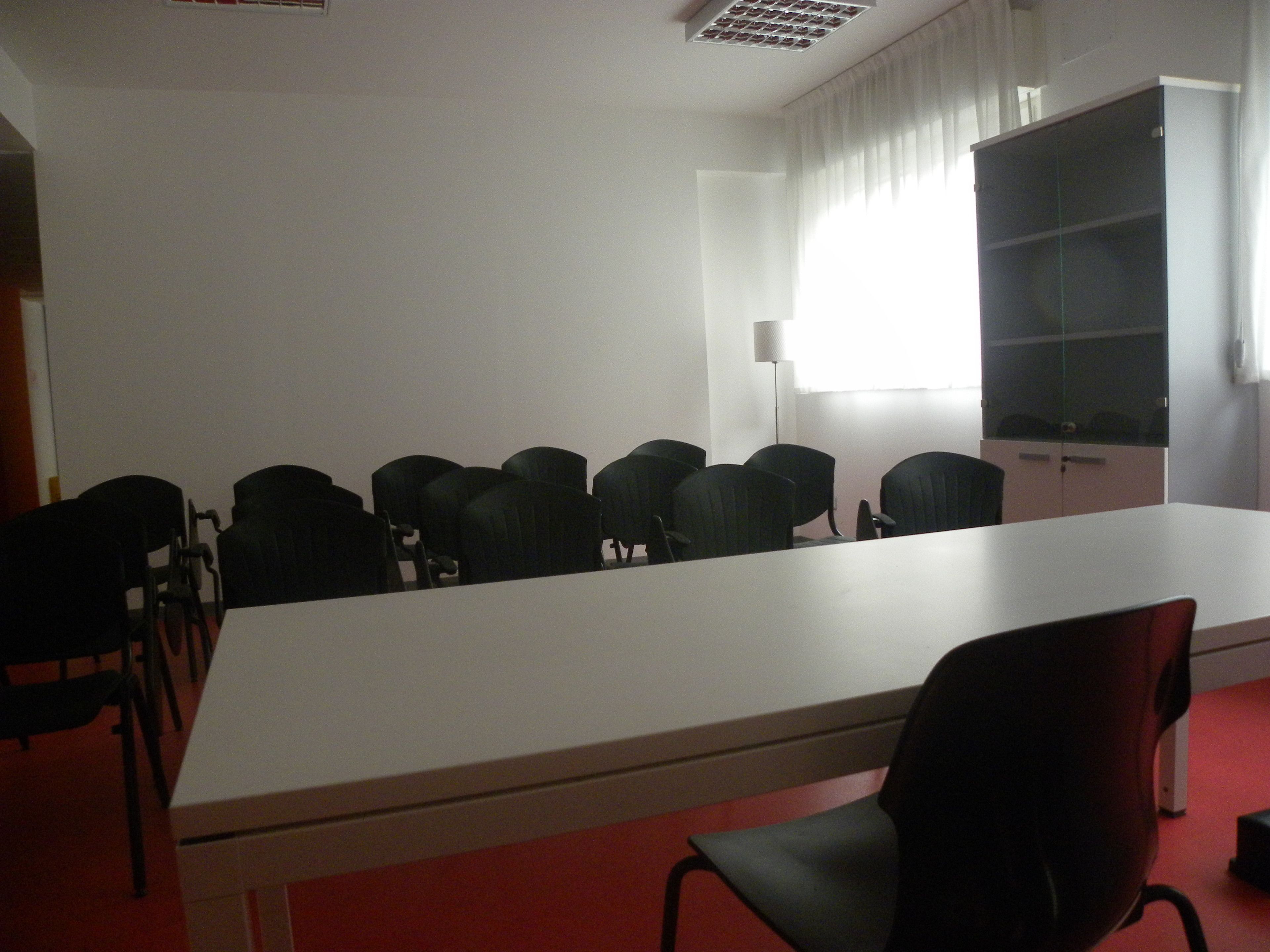 A conference room with a long table and multiple chairs.