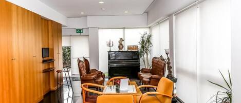 A modern lobby with a piano, leather chairs, and a wooden panel wall.