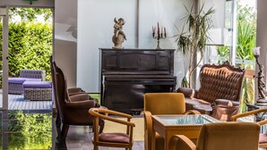 A modern lounge with a piano, comfortable seating, and a glass table. - Hotel Columbano (Peso da Régua)