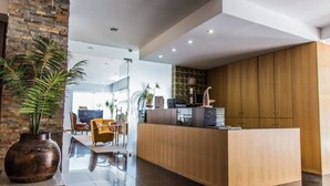 A modern kitchen with a wooden island, a large potted plant, and a view into the living area. - Hotel Columbano (Peso da Régua)