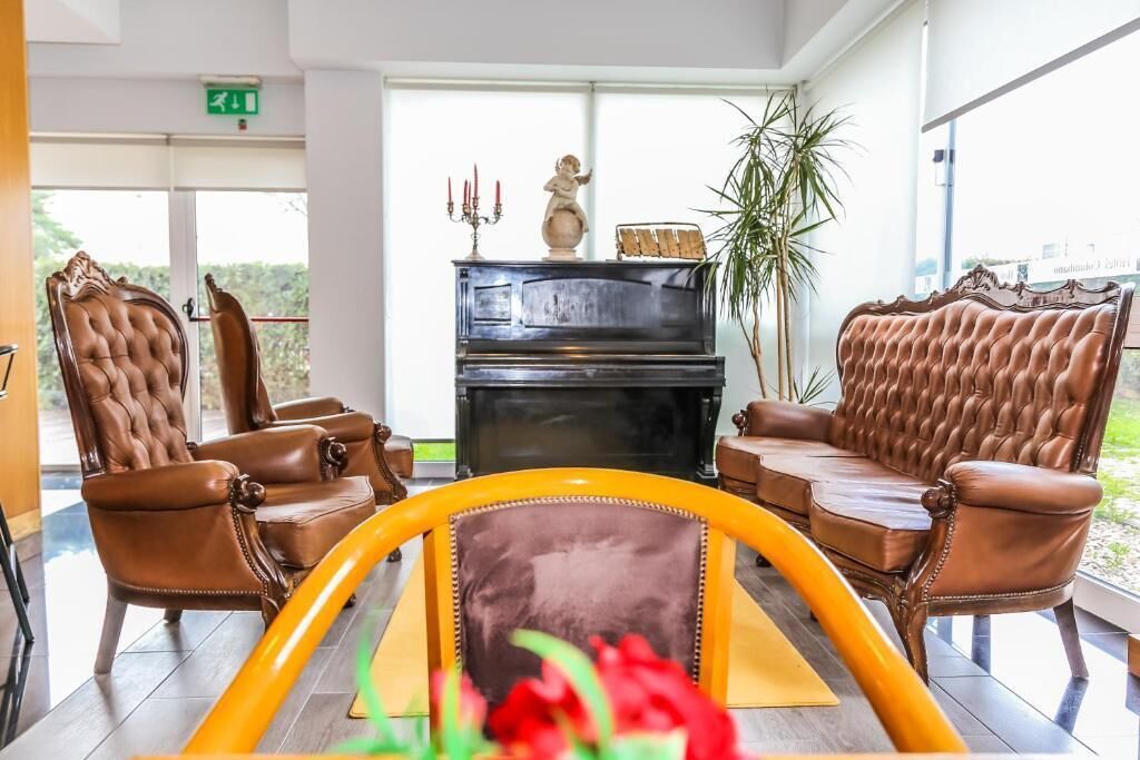 Una hall con poltrone in pelle, un pianoforte e un'ampia finestra con vista.