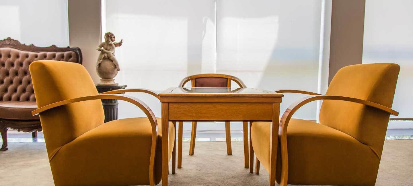A room with a wooden table and two mustard-colored chairs.