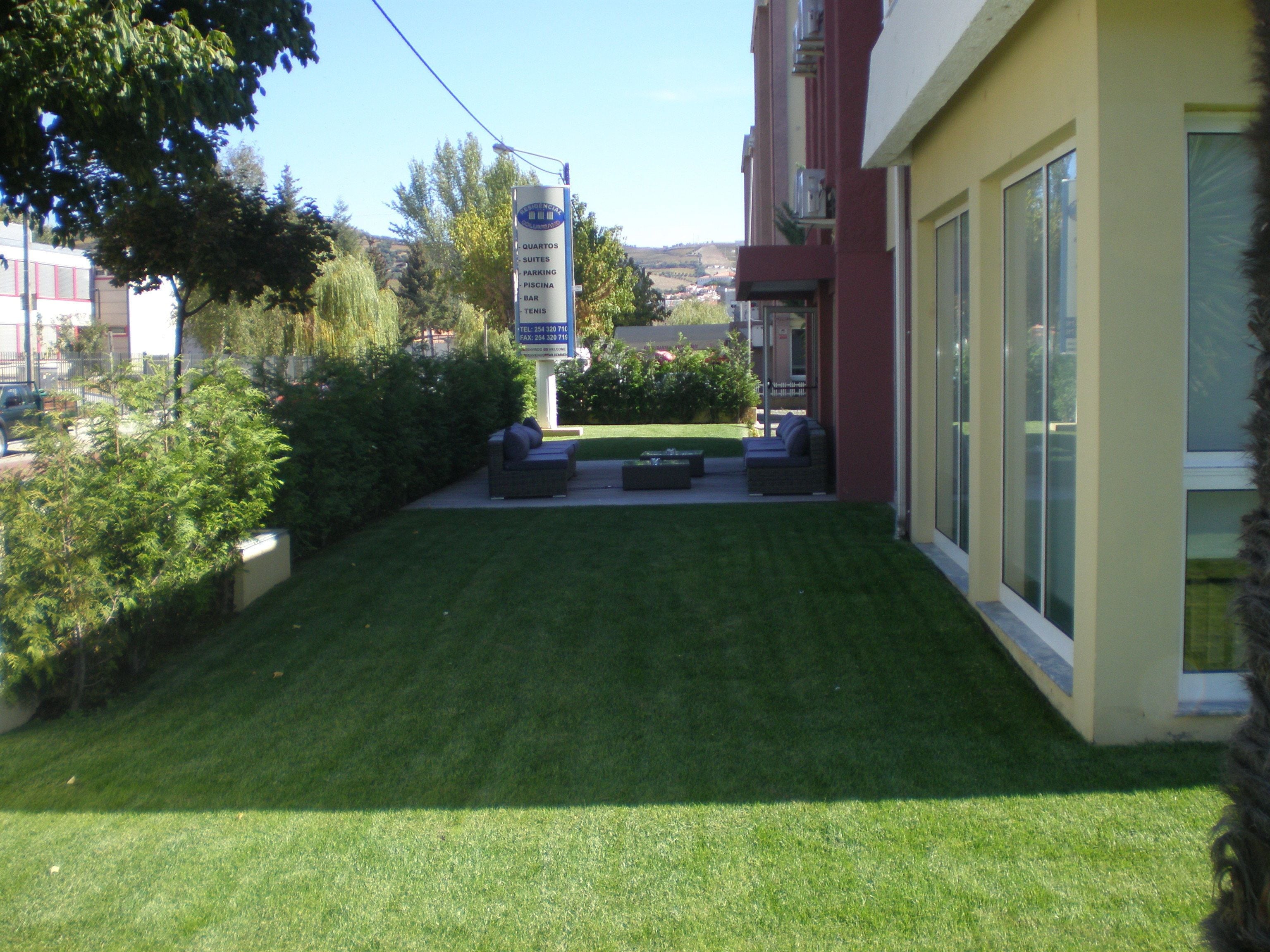 A well-maintained lawn with outdoor seating and a sign indicating hotel amenities.