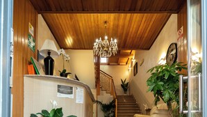 A hotel reception area with a red carpet, a staircase, a chandelier, and potted plants. - Hotel Residence Sestriere (Moncalieri)