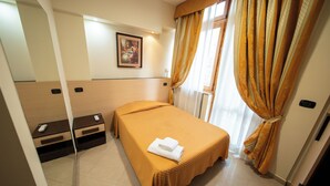 A hotel room with a bed, a desk, a chair, a painting on the wall, and curtains. - Hotel Residence Sestriere (Moncalieri)