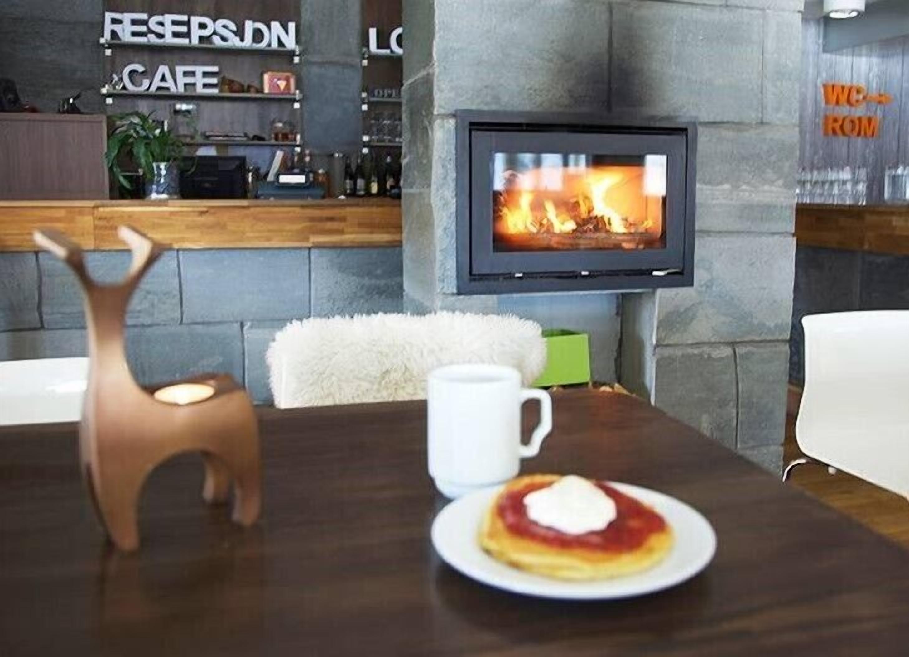 A cozy seating area with a fireplace, a table with a plate of food and a cup, and a decorative deer figure.