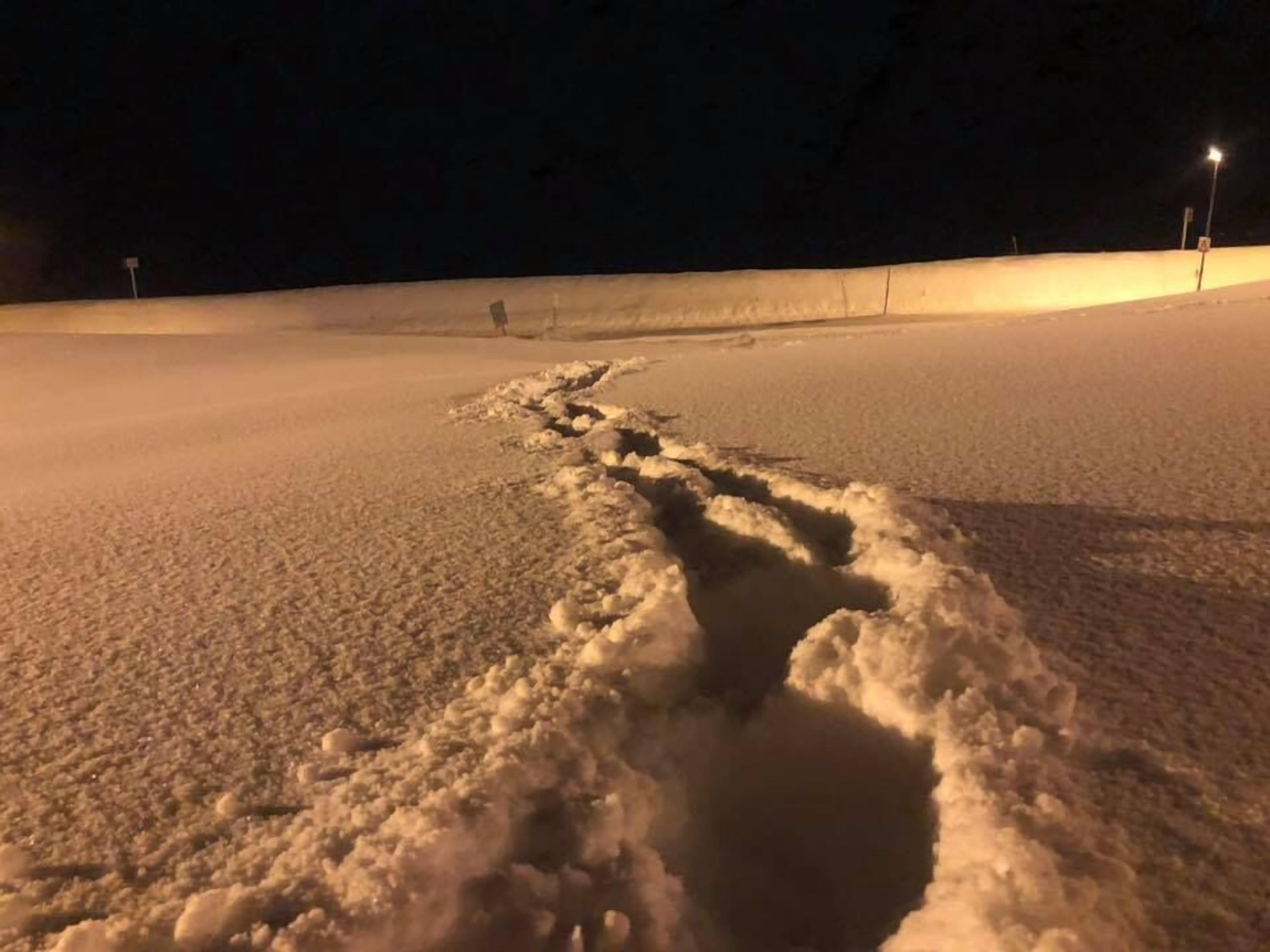 A snow-covered path with footprints leading through it.