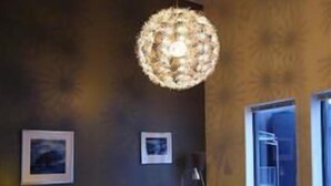 A modern living room with a dark wall, a round chandelier, a sofa, a coffee table, and two chairs. - Hordatun Hotel (Ullensvang)