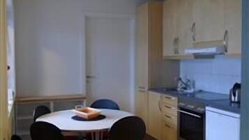 Una cocina compacta con comedor, armarios de madera y un refrigerador pequeño.