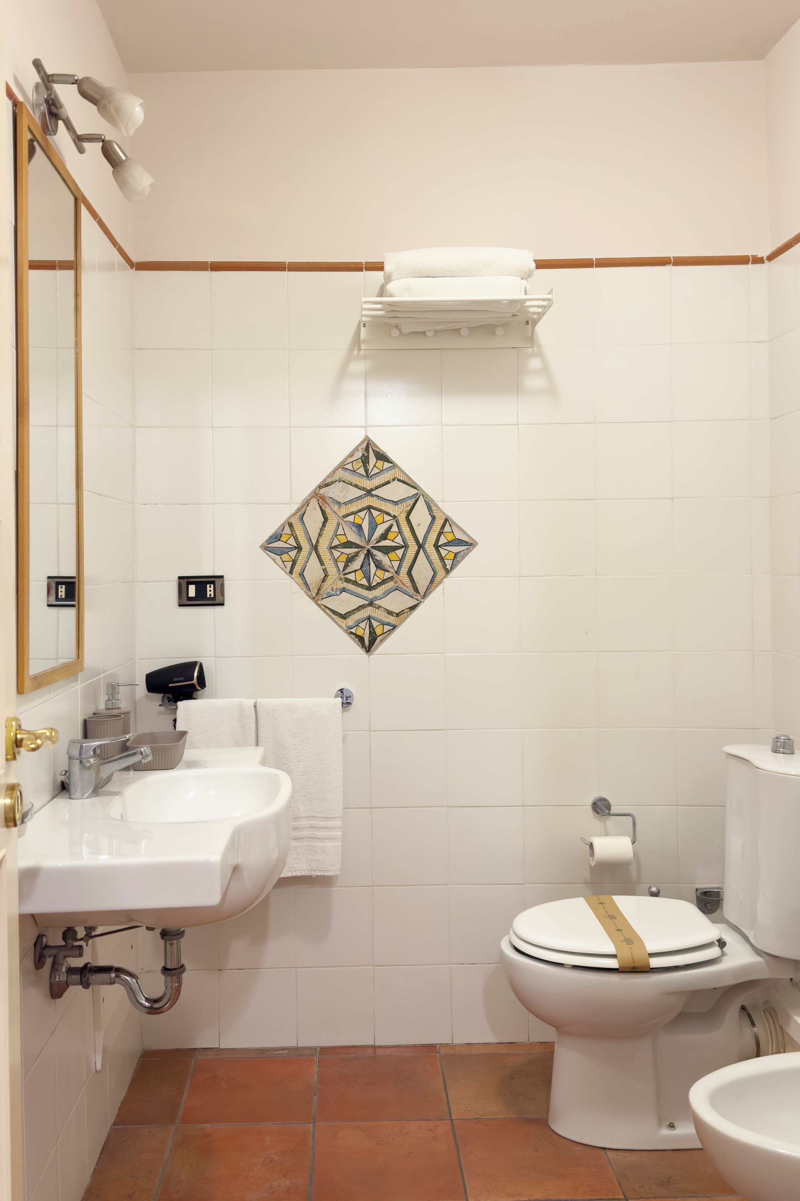 Une salle de bain avec un lavabo blanc, des toilettes et un miroir.