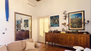 Una sala de estar con un sofá color beige, un mueble de madera y obras de arte en las paredes.